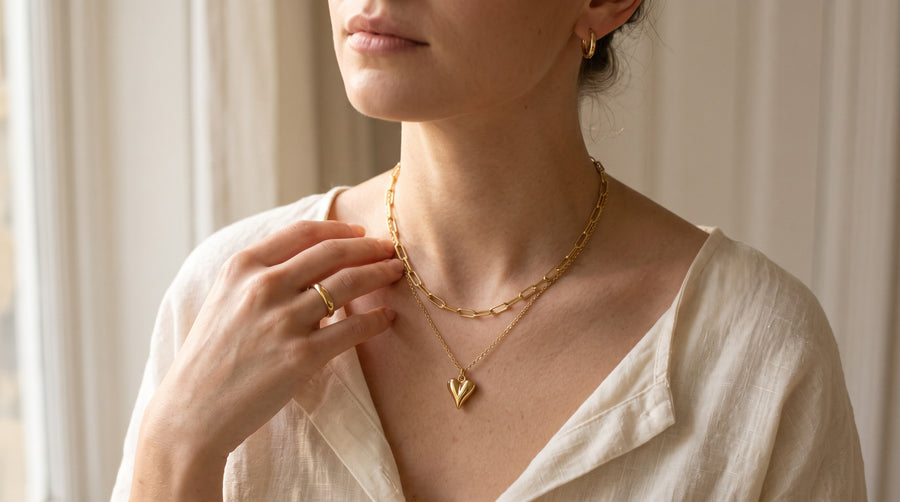 Gold heart necklace, huggie earrings and band ring worn together, illustrating what is gold vermeil