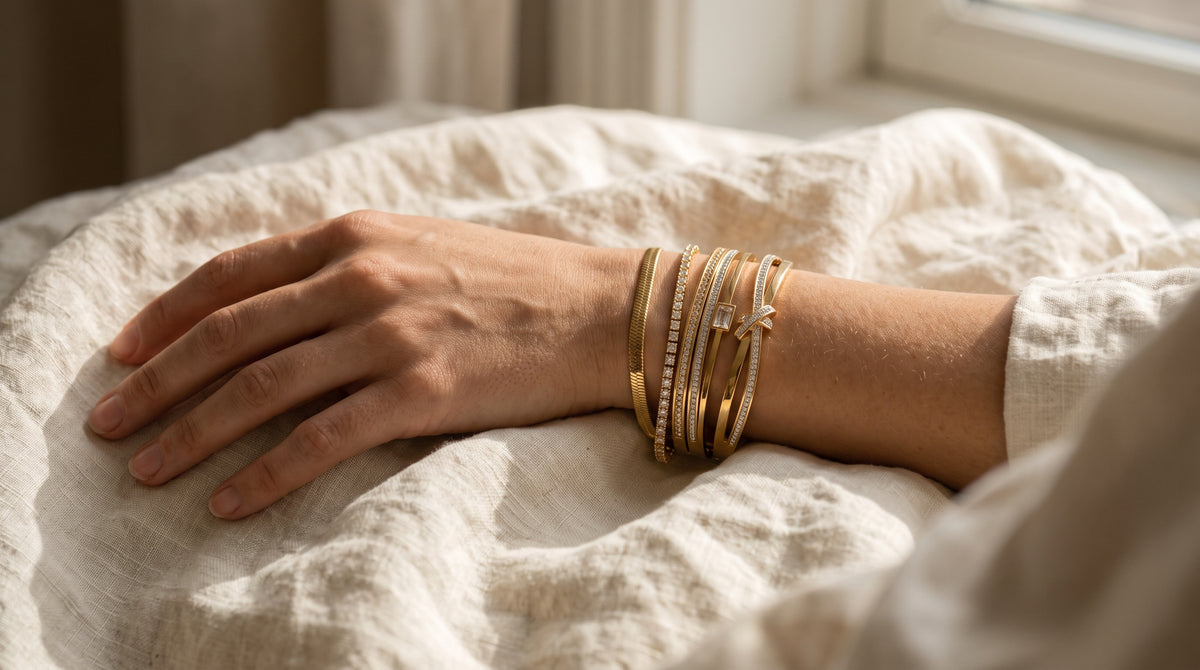 Wrist wearing a gold chain, tennis and bangle bracelets, illustrating a bracelet size chart fit