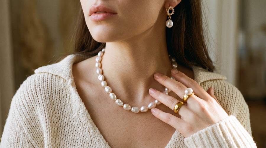 Woman wearing a baroque pearl necklace, pearl earrings and a pearl ring: pearl necklace meaning and style