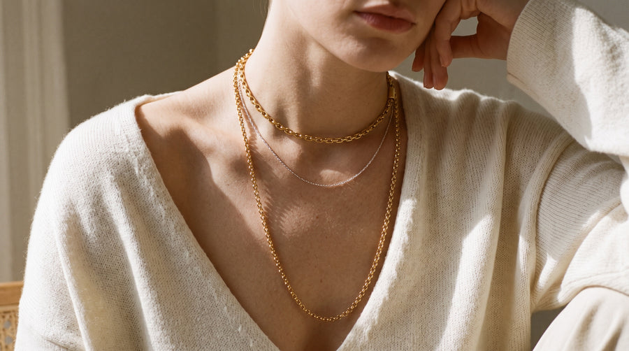 Necklace length chart in practice: a choker, a collarbone chain and a long chain worn on one woman