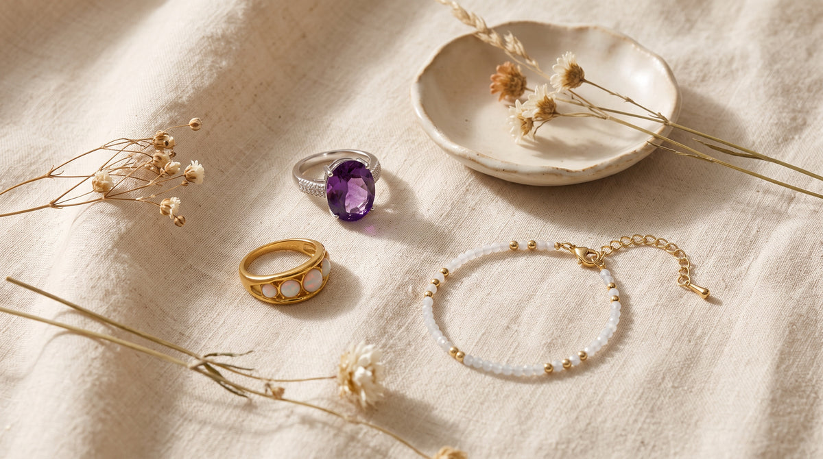 Birthstones by month: amethyst ring, opal ring and moonstone bead bracelet on cream linen