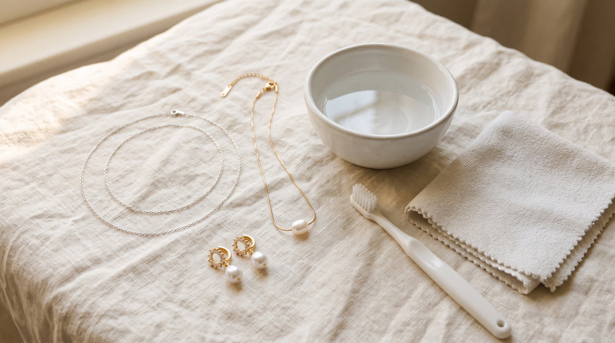 Silver chain, pearl necklace and pearl earrings beside a bowl, soft brush and cloth: how to clean jewelry at home