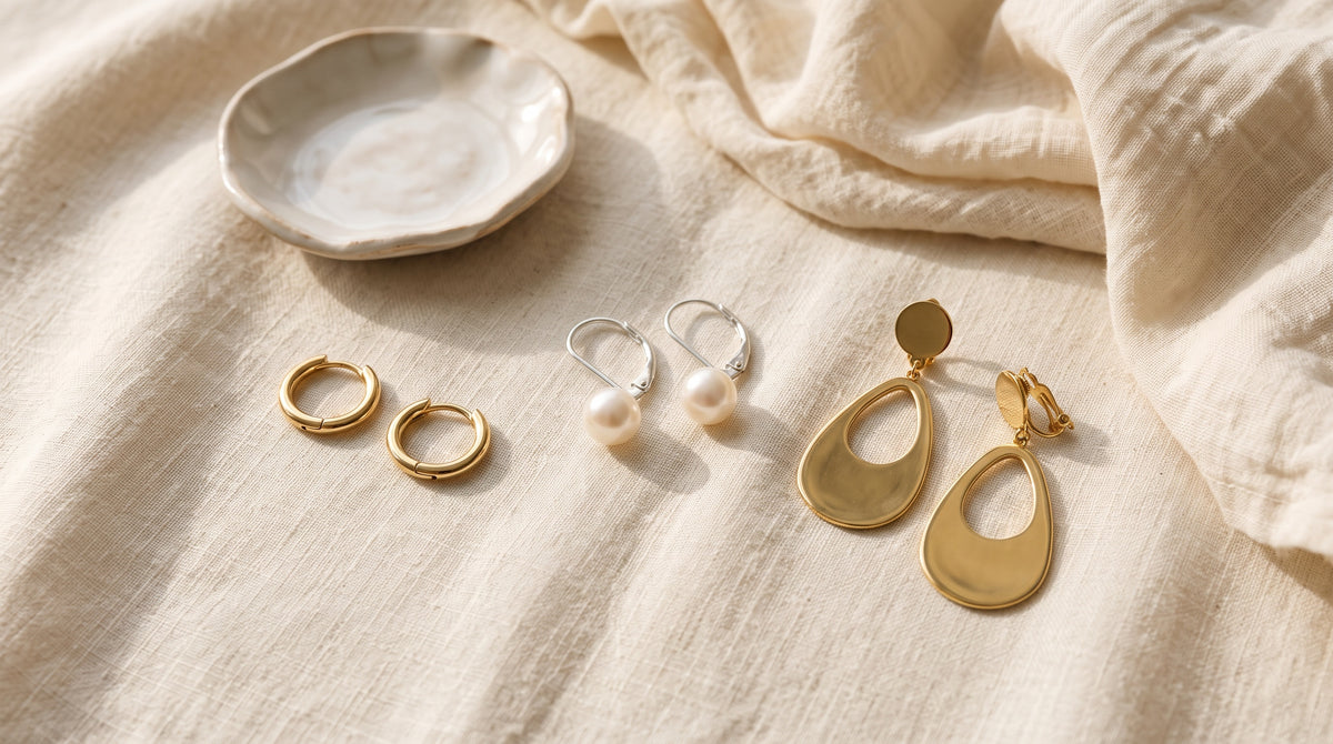 Hypoallergenic jewelry ideas: huggie earrings, pearl leverbacks and clip-on earrings on cream linen