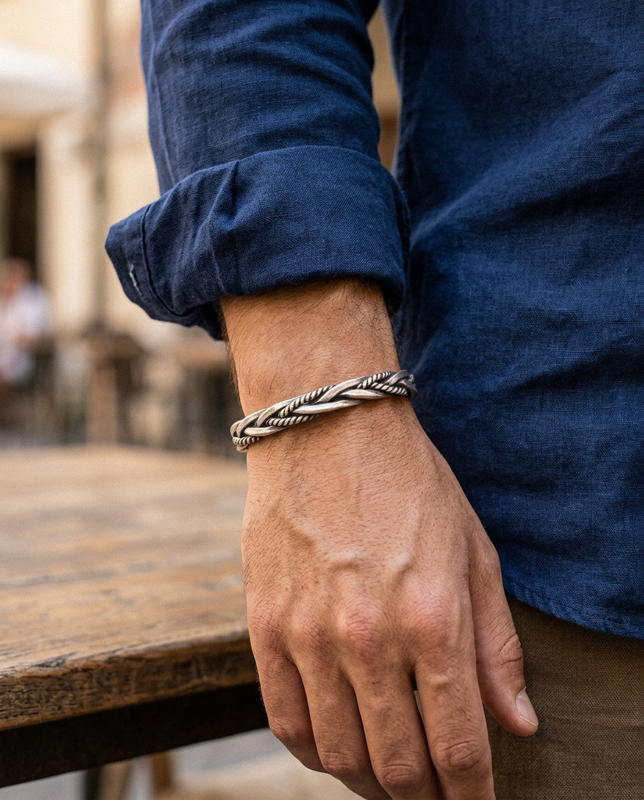 Twisted silver bangle worn on a man's wrist with a gray T-shirt