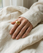Bague dôme dorée portée à l’index avec des bagues fines