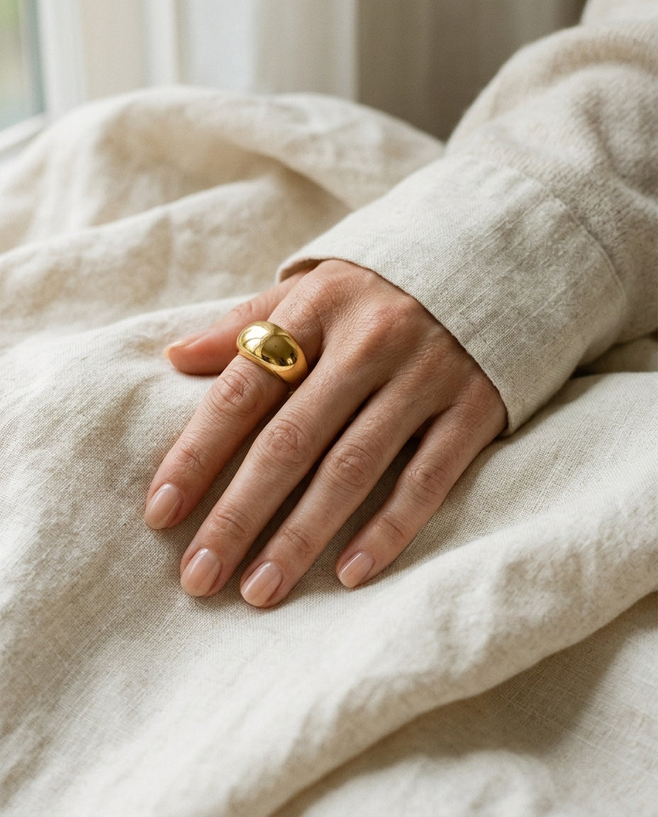 Bague dôme dorée portée à l’index avec des bagues fines