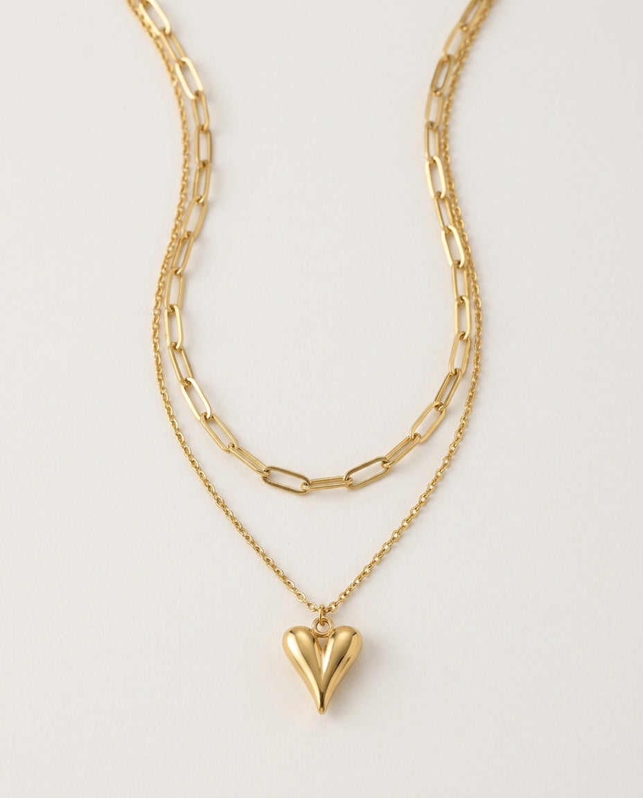 Gold heart necklace with a paperclip chain layered over a heart pendant