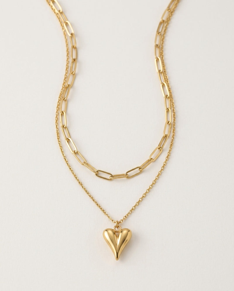 Gold heart necklace with a paperclip chain layered over a heart pendant