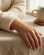 Bracelet MAMA doré porté à un poignet fin, manche en maille blanche