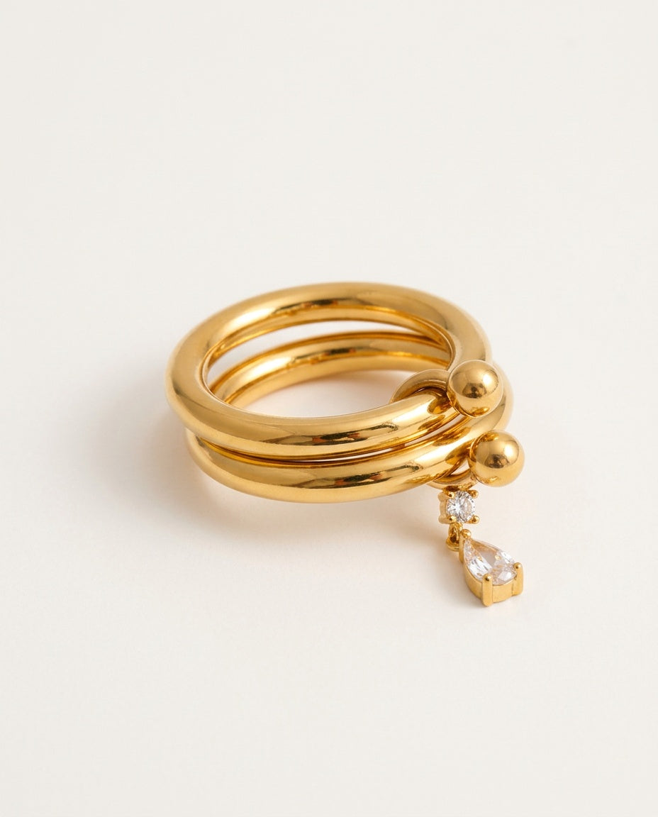 Gold charm ring with two slim bands and a dangling zirconia teardrop