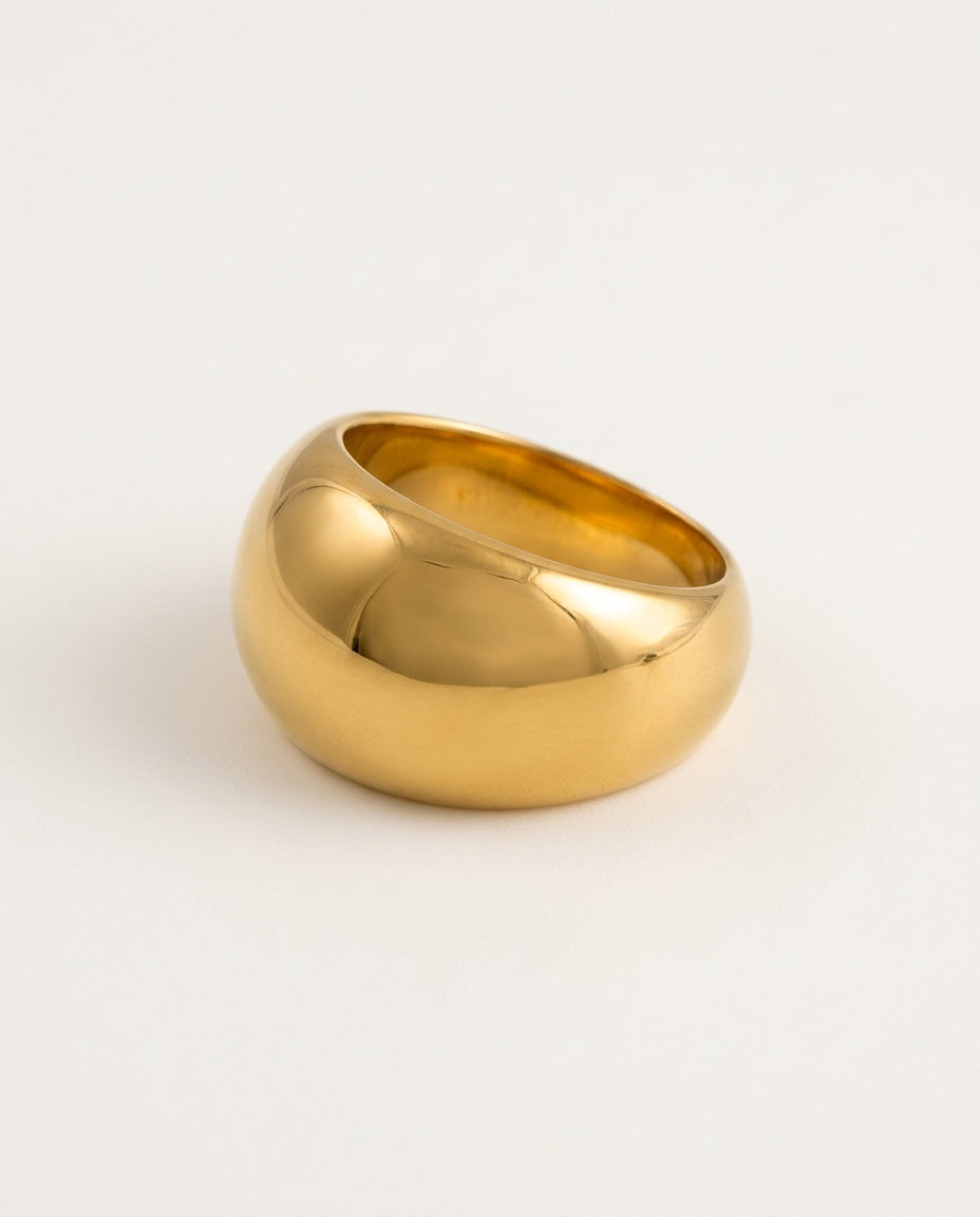 Grosse bague dôme dorée et brillante sur fond blanc