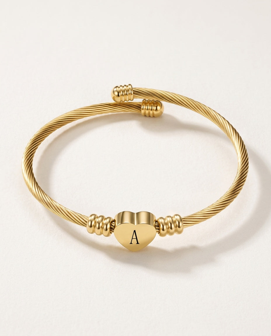 Charm bangle in gold-tone twisted cable with an initial heart charm