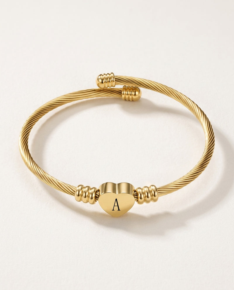 Charm bangle in gold-tone twisted cable with an initial heart charm