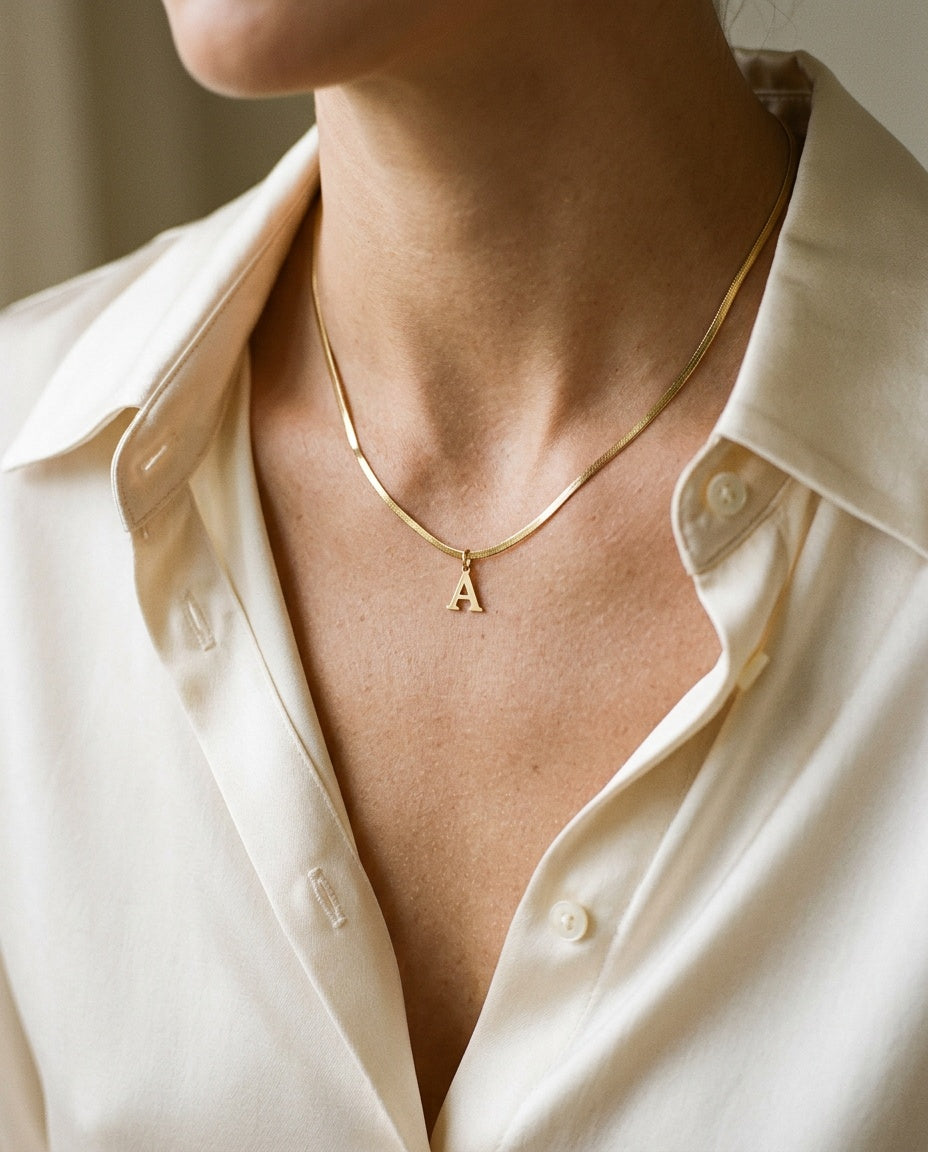 Gold letter pendant worn on the collarbone with a white top