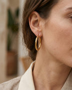 Gold twisted hoop worn on the ear with hair tied back