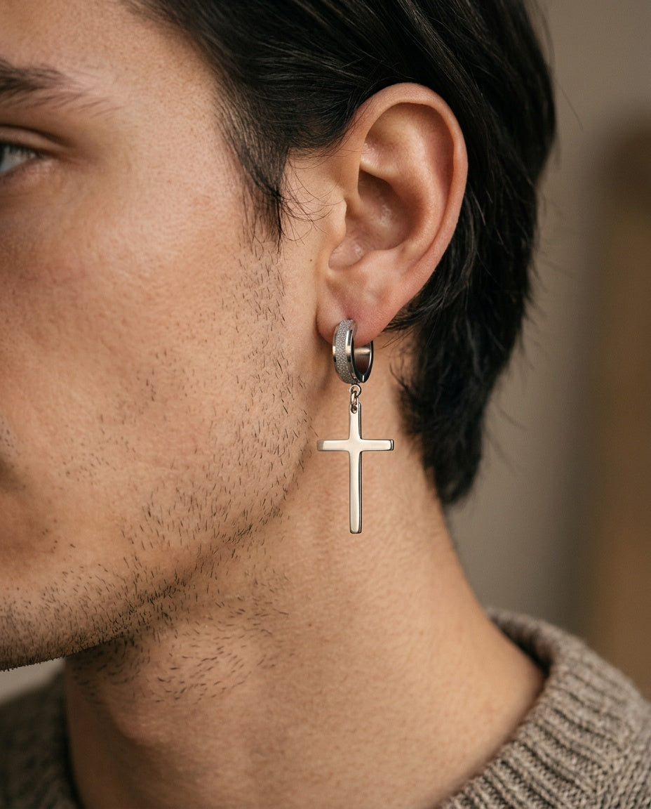 Small cross huggie earring worn on a man's ear