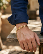 Man's wrist wearing a gold-tone steel bean link chain bracelet