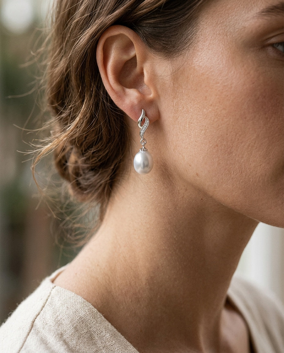Woman wearing silver earrings with white freshwater pearls and hair pulled back
