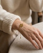 Bracelet femme trèfle porté au poignet avec d'autres bracelets dorés