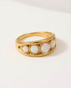Opal ring with a row of white opals on a wide gold band, packshot