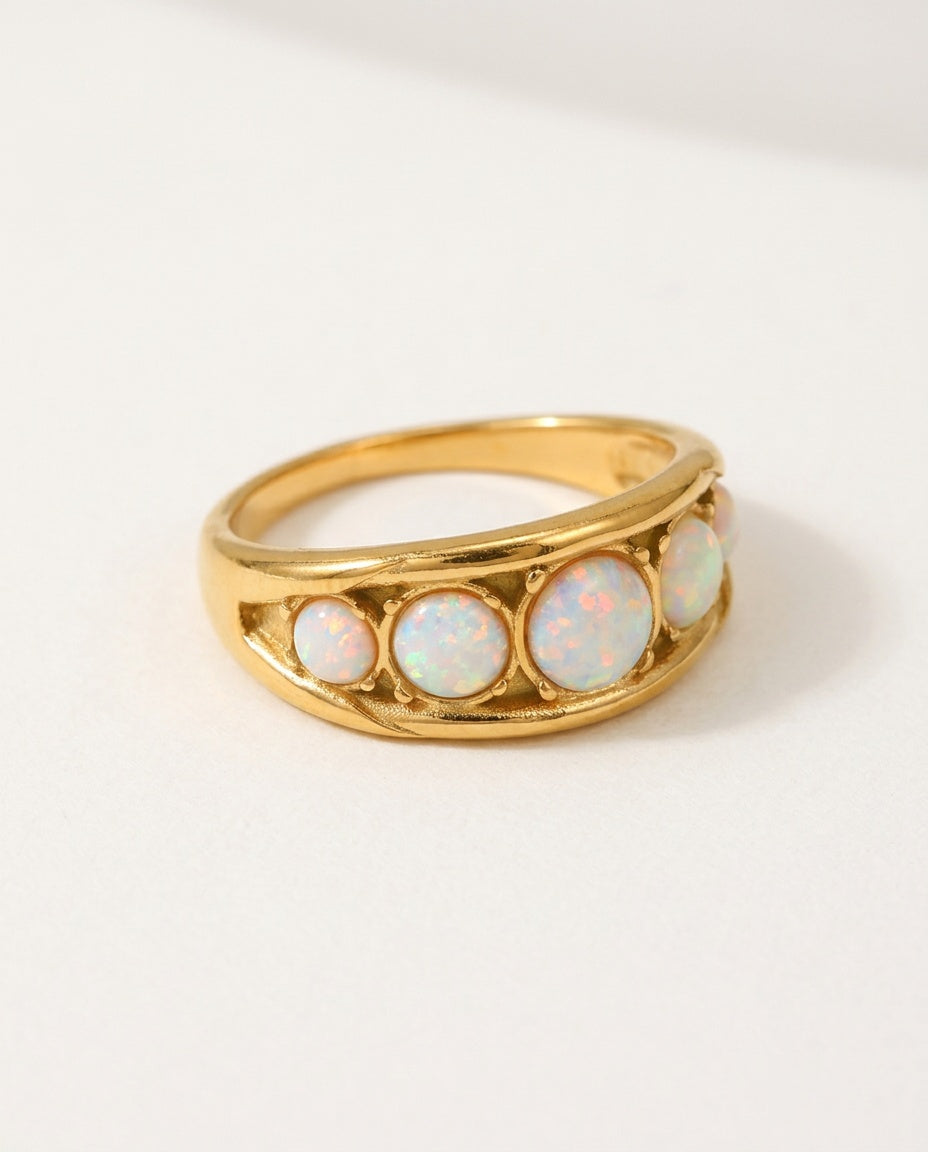 Opal ring with a row of white opals on a wide gold band, packshot