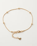 Gold anklet with small round beads on a white background
