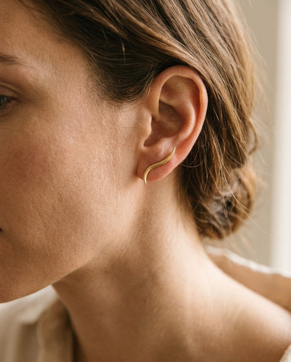 Ear climber earrings worn along the edge of the ear