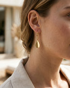 Gold teardrop earrings worn with hair pulled back