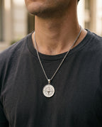 Compass medallion necklace worn over a gray T-shirt