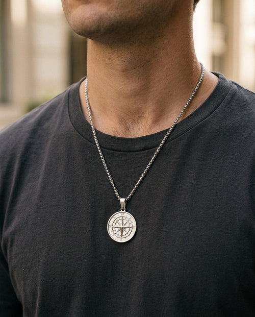 Compass medallion necklace worn over a gray T-shirt