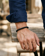 Wrist wearing a matte black stone bead bracelet next to a watch