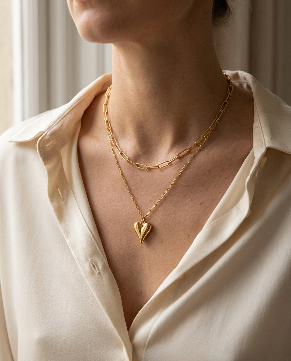 Heart necklace worn with an open collar, two layers visible