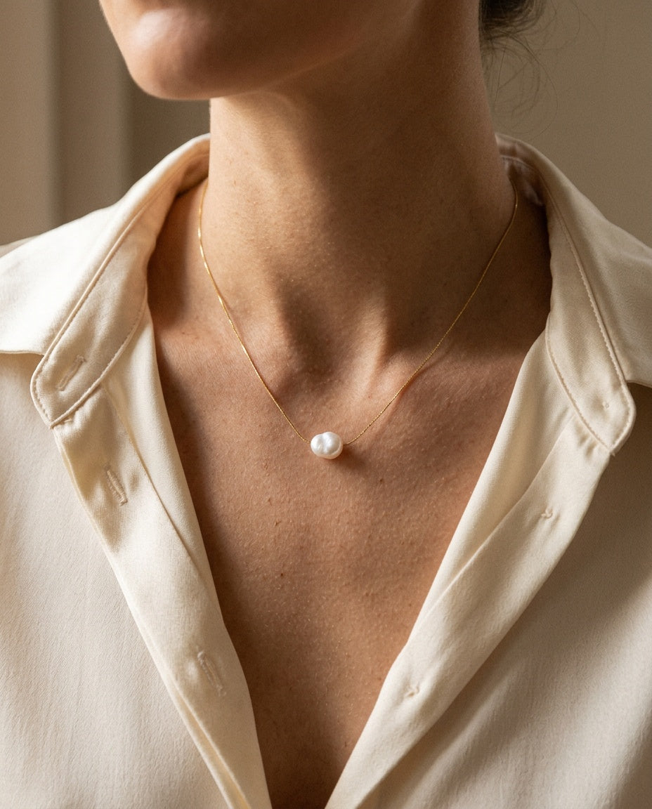 Pearl charm necklace worn close to the neck with an open collar
