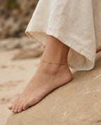 Gold anklet worn on a bare ankle with sandals