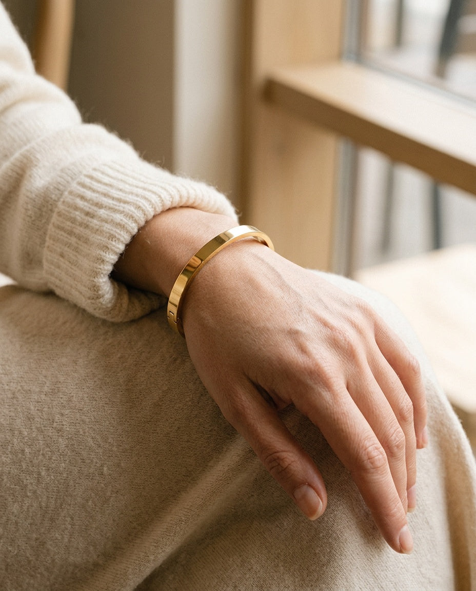 Wrist wearing a slim engraved steel bangle next to a watch