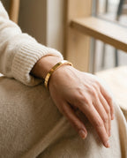 Wrist wearing a slim engraved steel bangle next to a watch