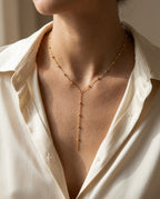 Woman wearing a gold Y chain with a drop falling down a V-neckline