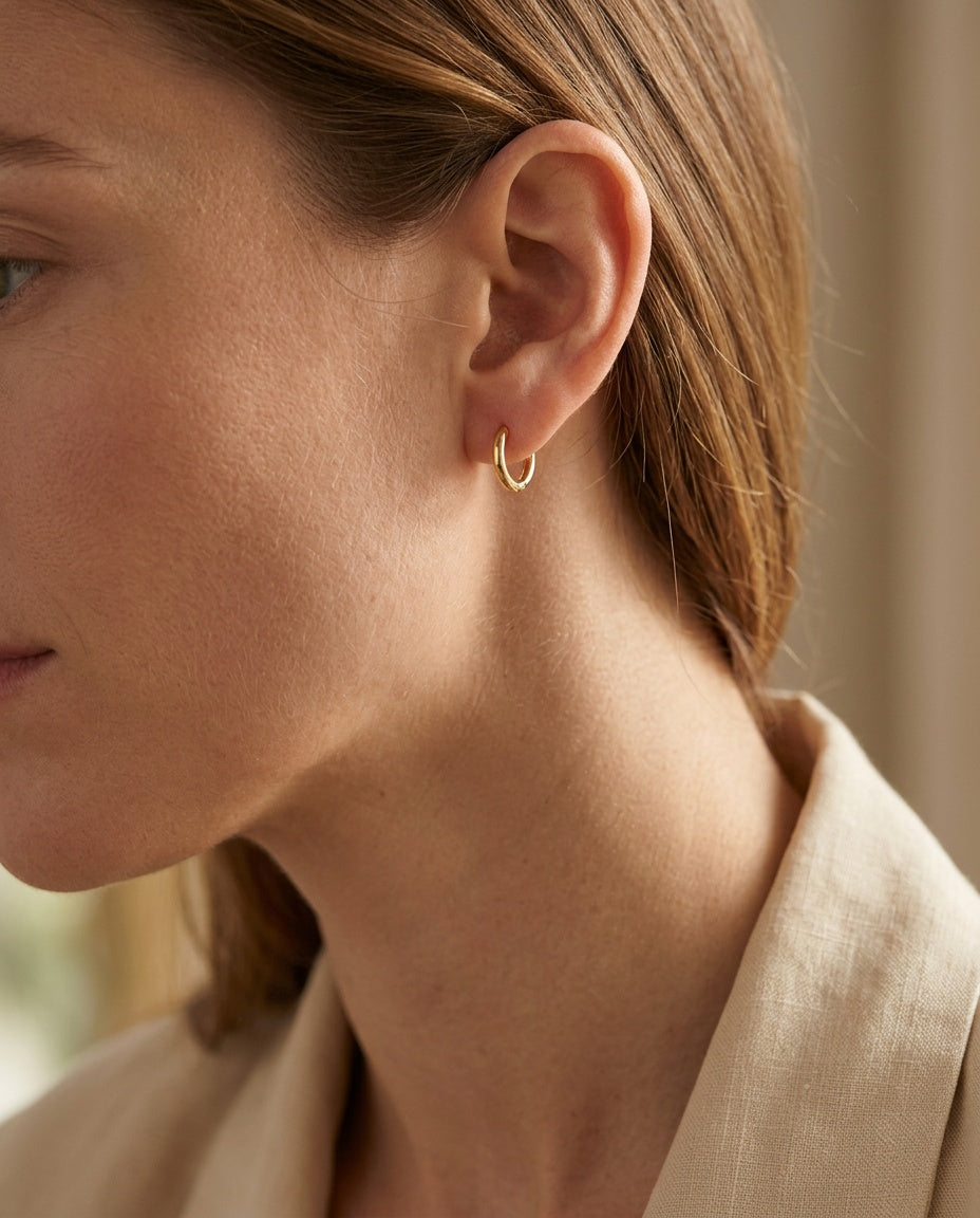 Small hoops worn in a stacked lobe with other earrings