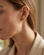 Small hoops worn in a stacked lobe with other earrings