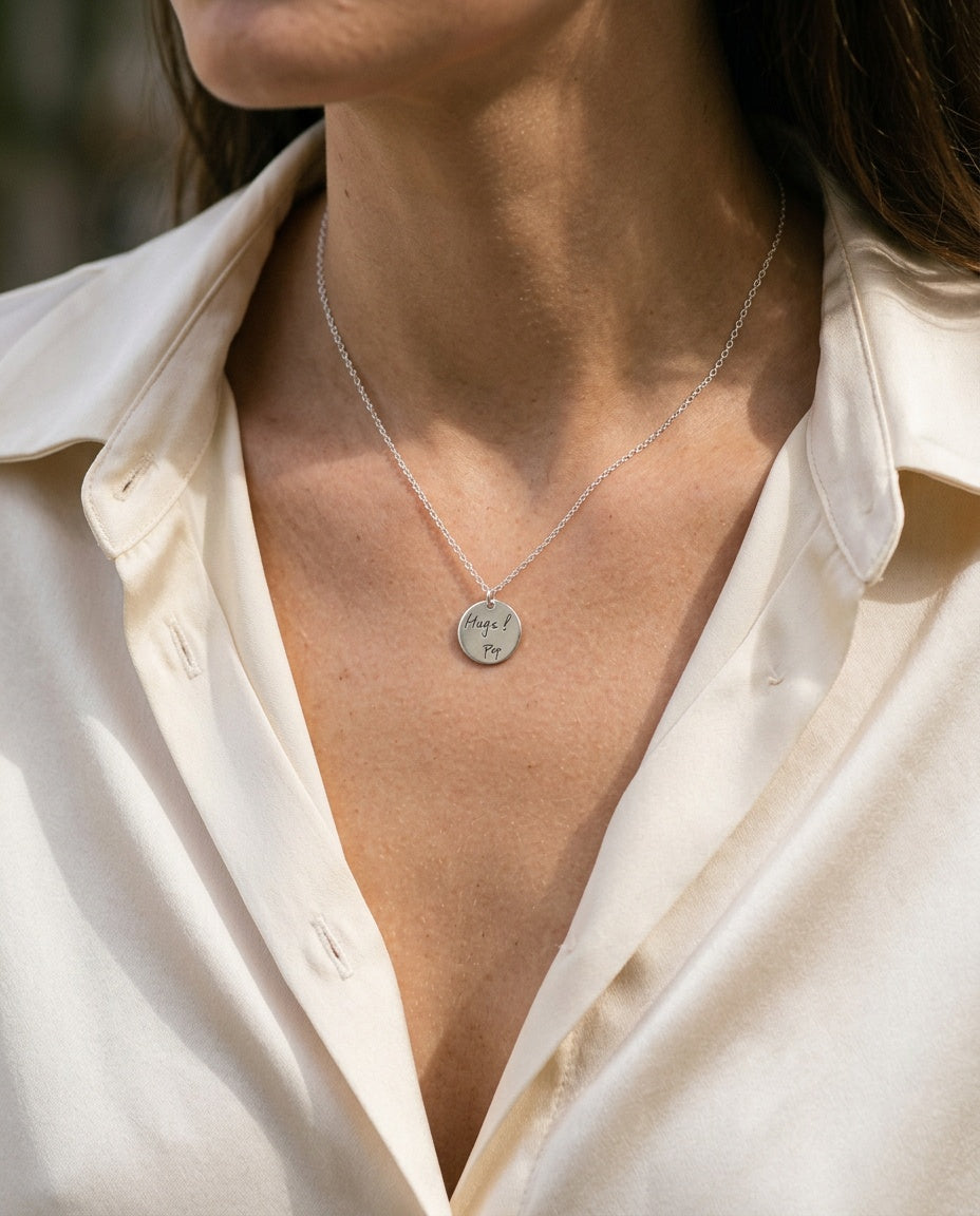 Engraved disc necklace worn below the collarbone