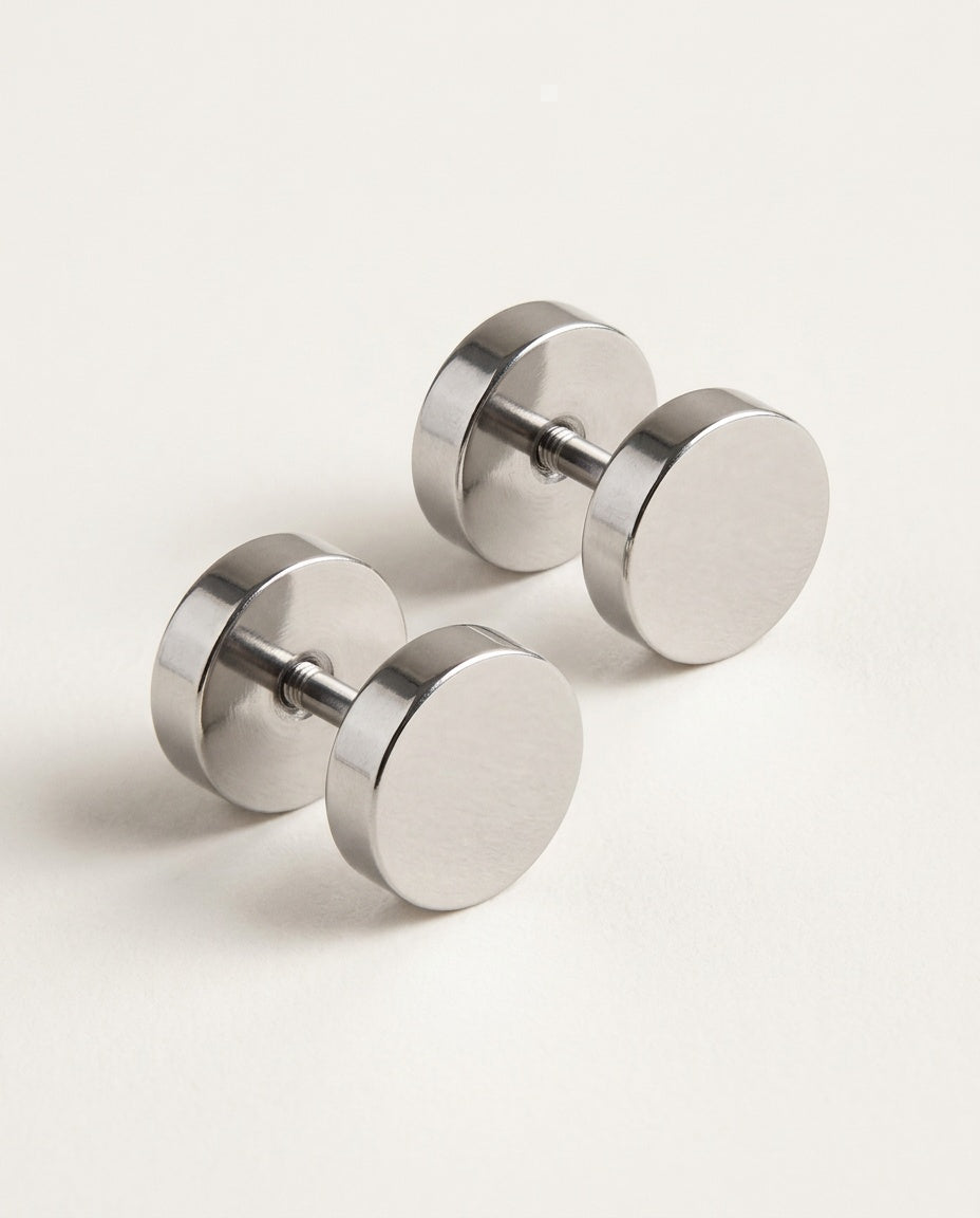 Mens stud earrings, flat round stainless steel discs on a plain background