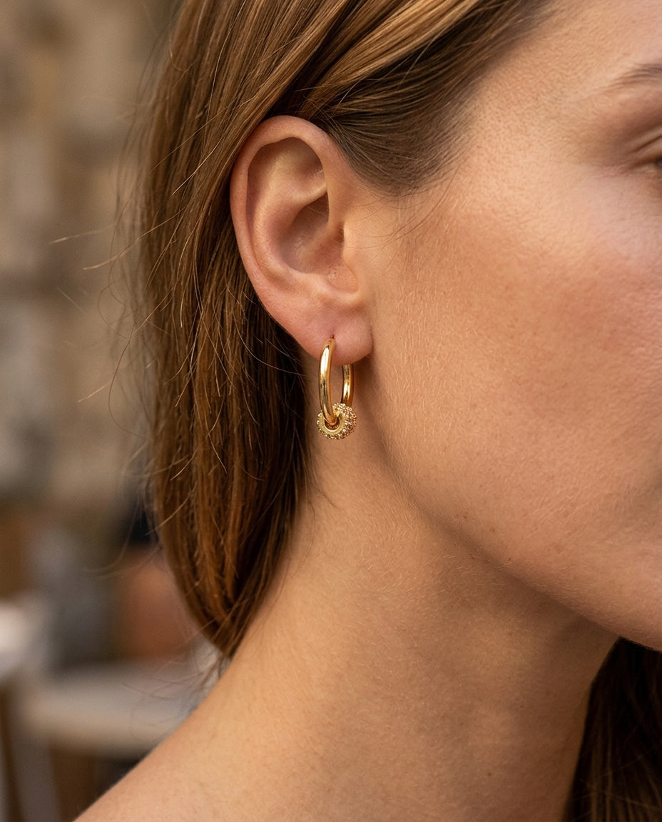 Gold charm hoop earrings worn on the lobe