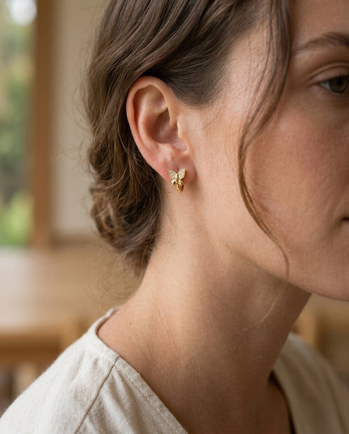 Butterfly earrings worn on the earlobe with hair tucked back