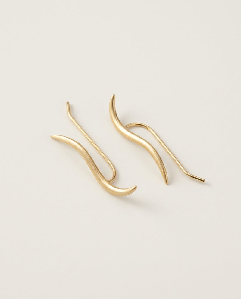 Gold ear climber earrings with a fine wavy line in sterling silver