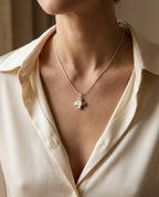 Cross necklace worn at the collarbone