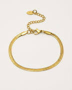 Gold chain bracelet in herringbone style on a light background