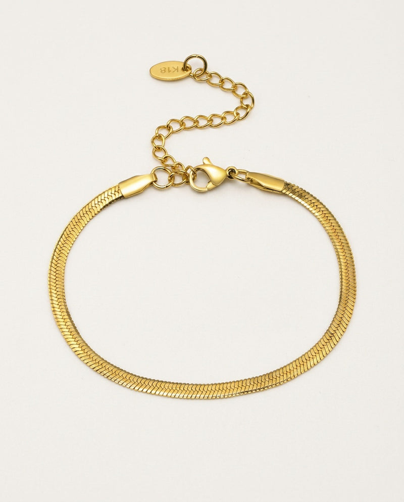 Gold chain bracelet in herringbone style on a light background