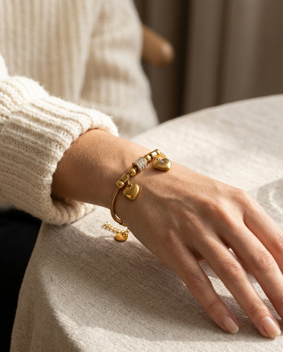 Gold charm bracelet worn on the wrist with a fine tennis bracelet