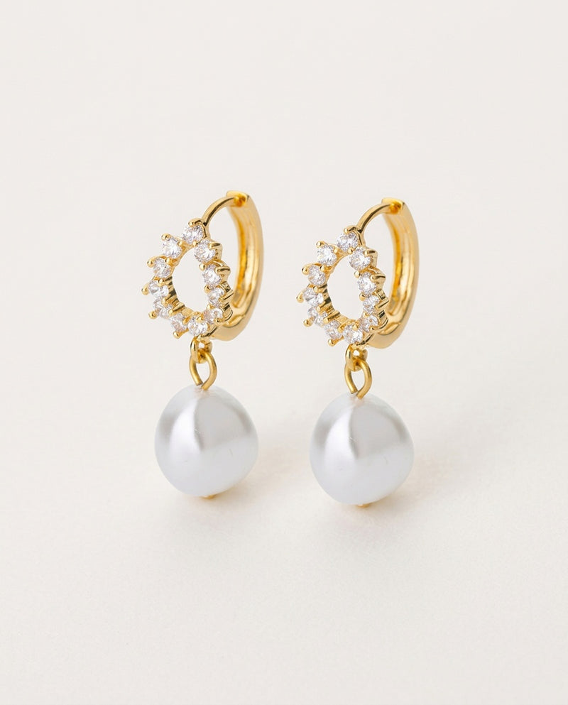 Gold pearl earrings with irregular round pearl drops, on white