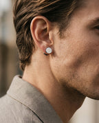 Flat silver disc stud worn on a man's earlobe